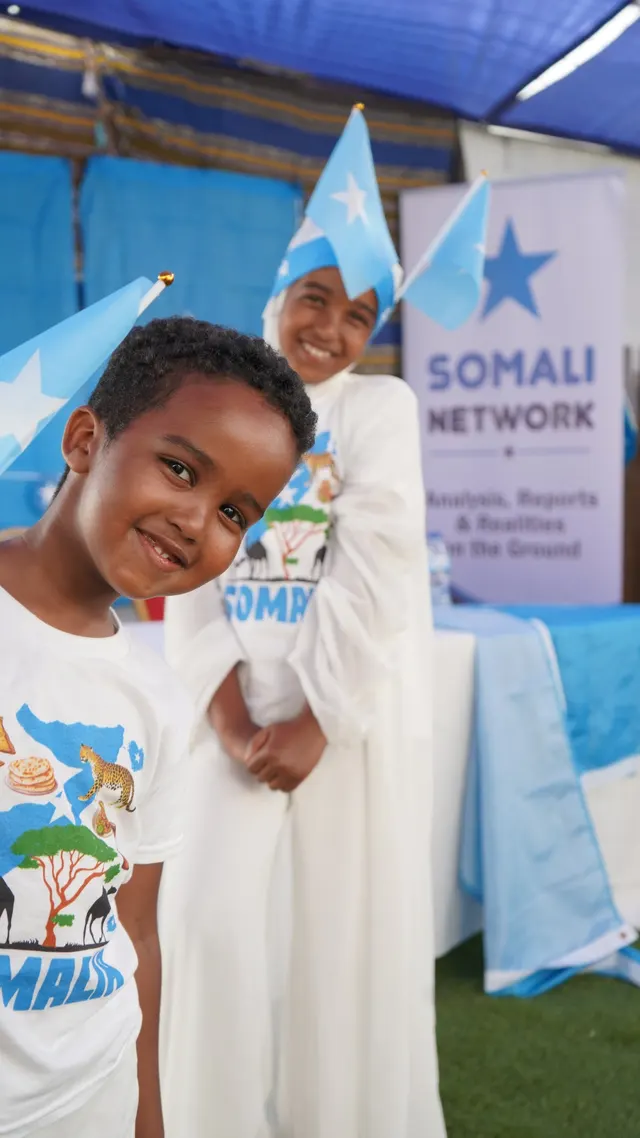 Two children in Somali flag hats at the Somali Network stall.