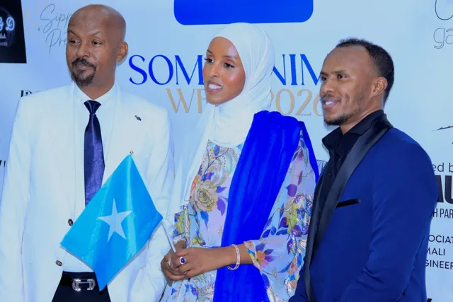 Three guests holding a Somali flag on the Somalinimo Week 2026 red carpet.